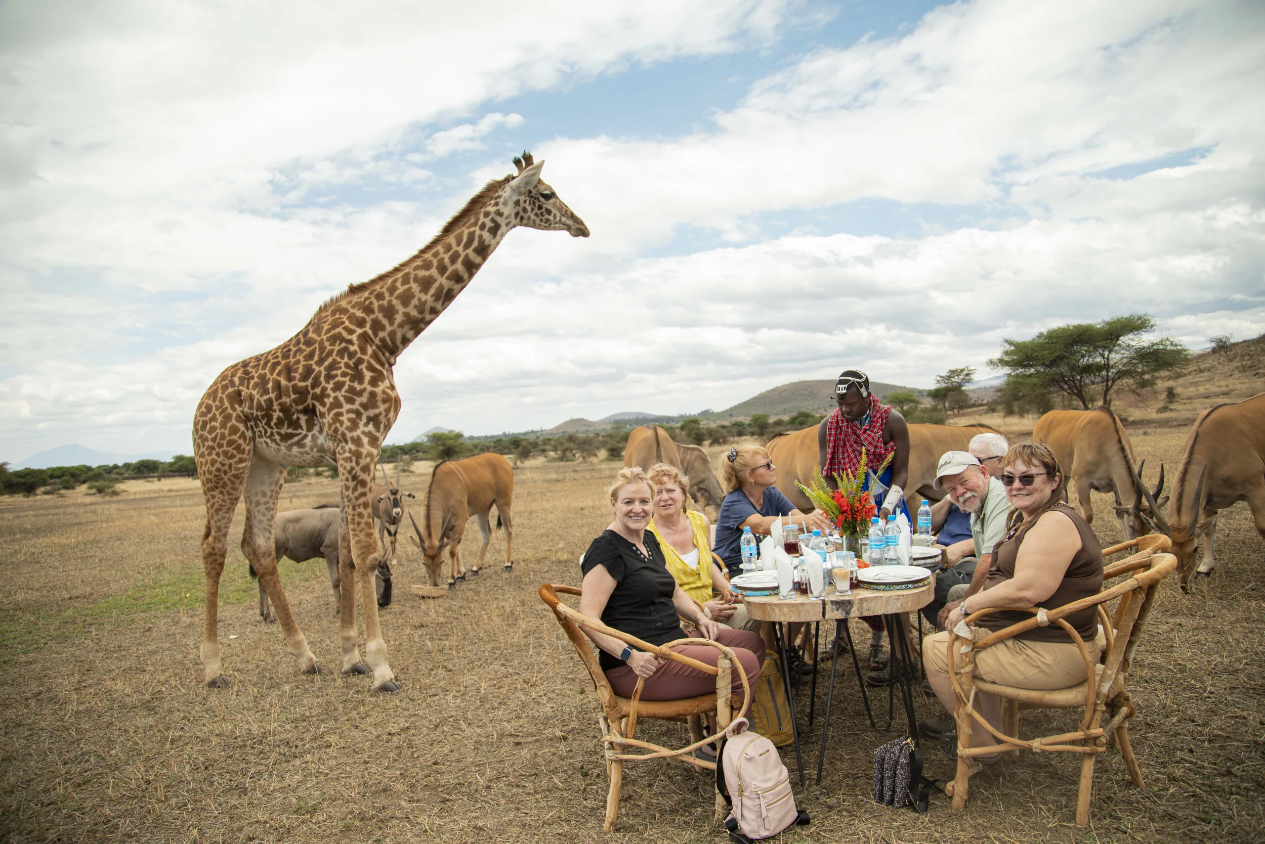 Guests enjoying a private bush lunch beside a giraffe